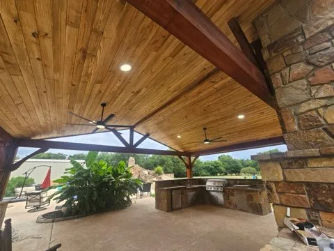 Lush outdoor patio with wooden deck, green plants, and outdoor seating under a clear sky.