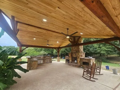 Lush outdoor patio with wooden deck, green plants, and outdoor seating under a clear sky.