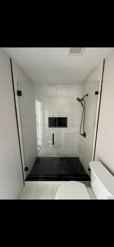 Modern bathroom with white tiles, freestanding tub, glass shower, and vanity mirror.