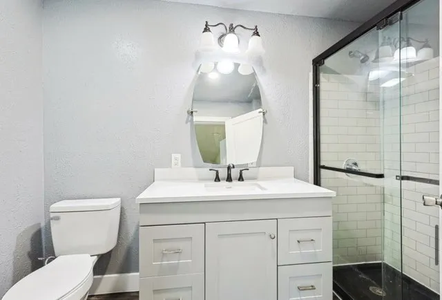 Modern bathroom with white tiles, freestanding tub, glass shower, and vanity mirror.